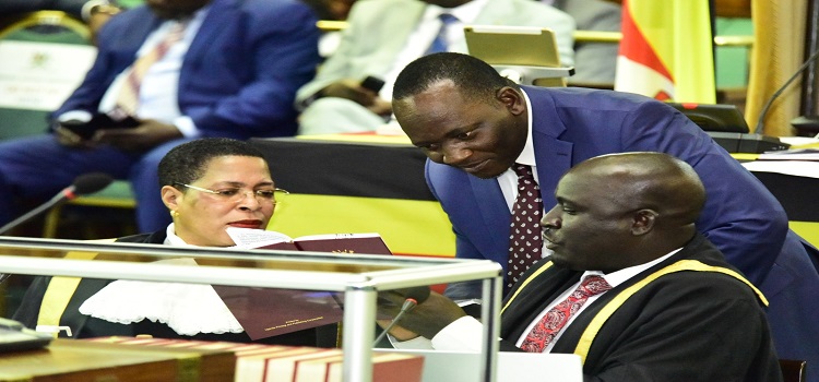 Speaker Anita Among (L)  and the Leader of Opposition, Hon. Mathias Mpuuga (C) are shown a clause in the Constitution 